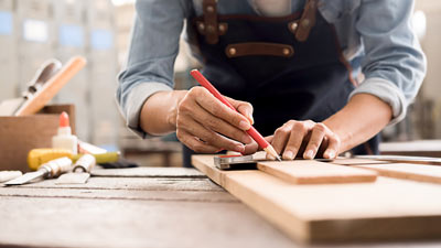 person marking wood with pencil in workshop using tools for woodworking projects and measuring techniques for two wood pieces