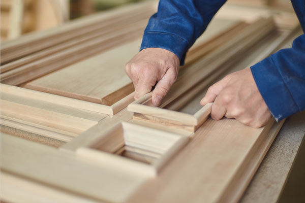 A person assembling wooden pieces on a workbench, focusing on precise fitting and craftsmanship in woodworking techniques.