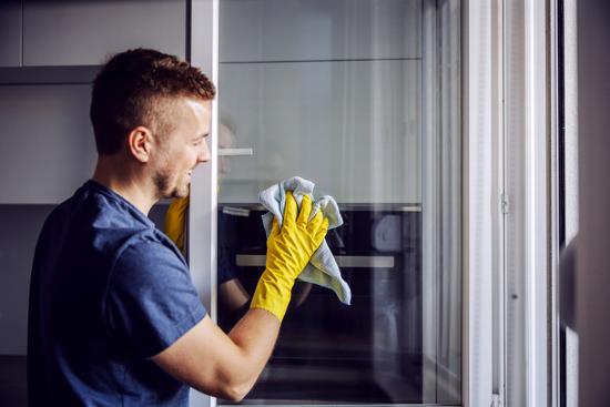 Man cleaning glass door in house